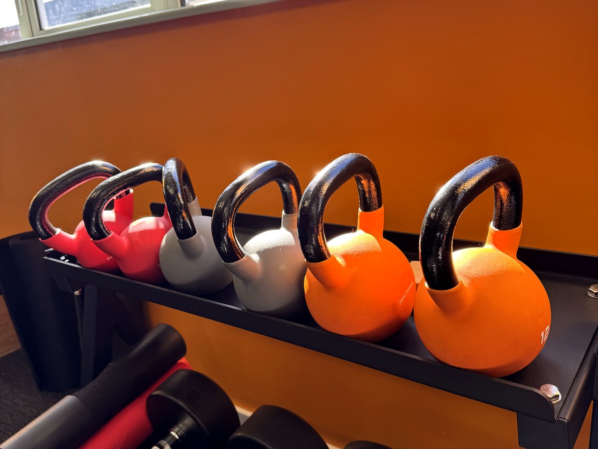 A rack of orange and red kettlebells on the gym floor at Keep Fit 4 U
